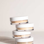Four round LAMAV Anti Ageing Mineral Foundation SPF 15 containers with white lids are stacked unevenly atop one another against a neutral background.