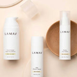 Three white bottles from the LAMAV Brightening Skin Discovery Pack (3 Pack) are displayed on a beige background with a tan ceramic dish.