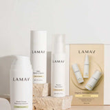 Three LAMAV skincare products from the Brightening Skin Discovery Pack are displayed with minimalist white packaging on a neutral background accented by stone props. A box labeled "Organic Skincare Essentials" features the LAMAV brand.