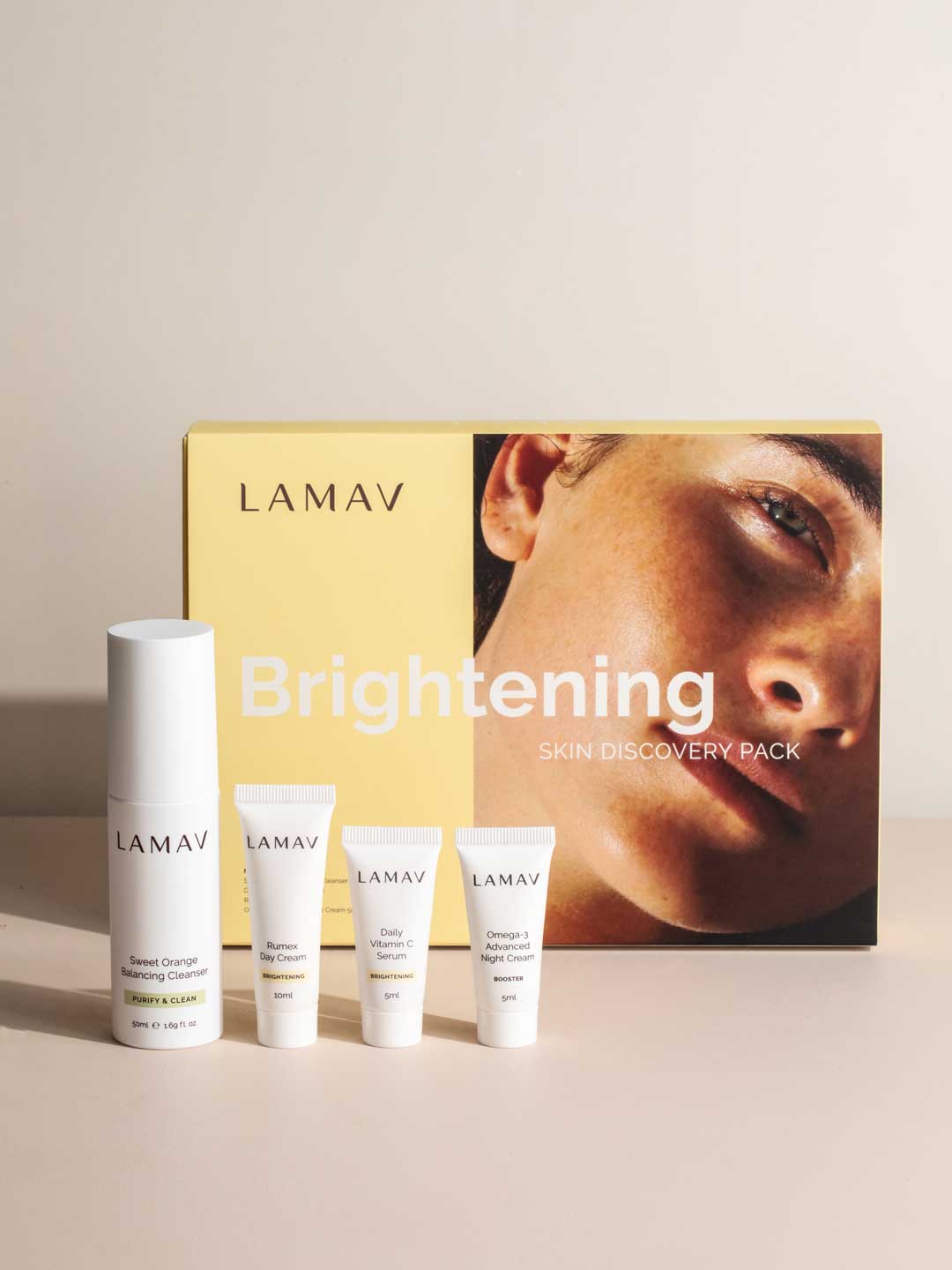 The LAMAV Brightening Skin Discovery Pack (4 Pack) is displayed with four white tubes and bottles for brightening, arranged before a yellow box showing a woman's face. Brand: LAMAV.