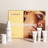 LAMAV Brightening Skin Discovery Pack (4 Pack) by LAMAV shown on a beige surface, with a yellow box featuring a woman's face and four white brightening products—a spray bottle, two small tubes, and a mini bottle. Great for organic skincare lovers.