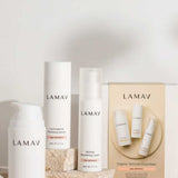 Three LAMAV Age-Defence Skin Discovery Pack products are displayed on stone blocks, with a branded box labeled "Organic Skincare Essentials Age-Defence" showcasing the anti-ageing range against a neutral background.