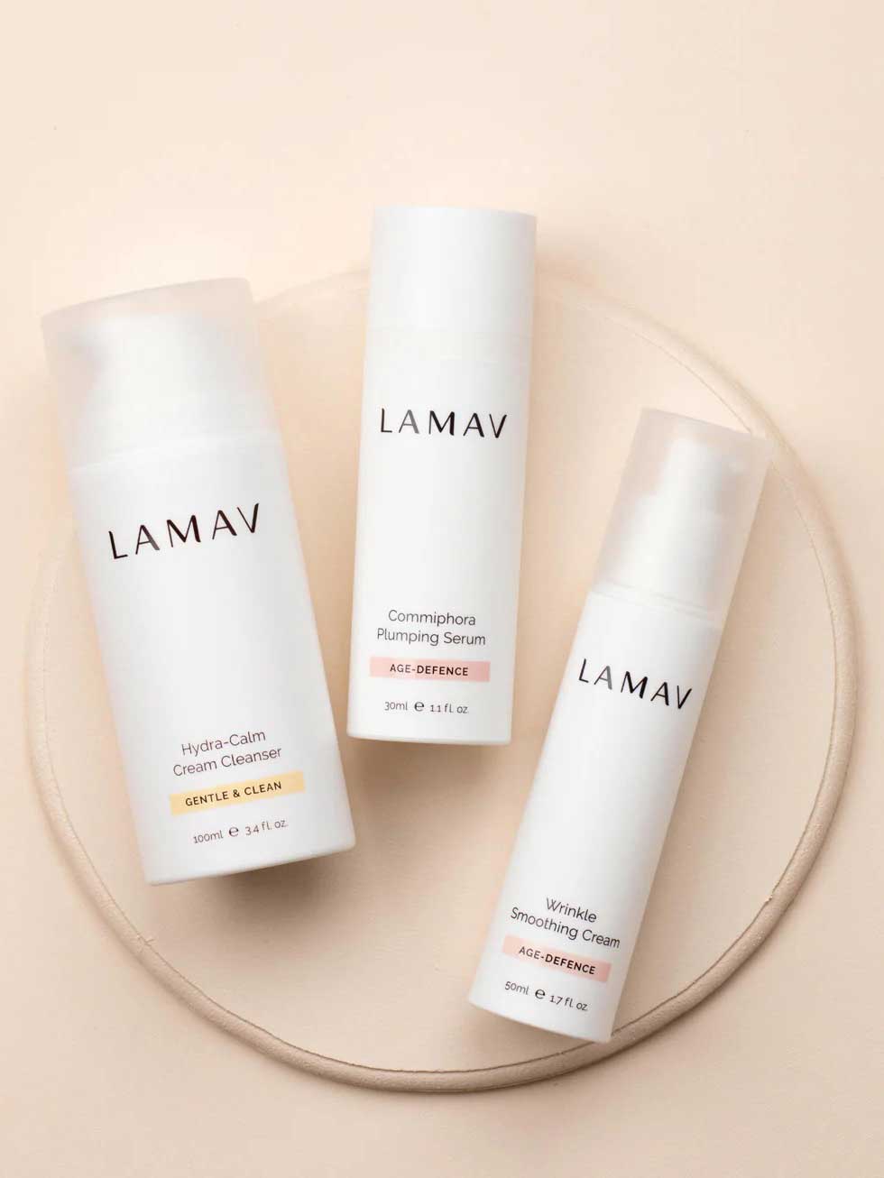 The LAMAV Age-Defence Skin Discovery Pack (3 Pack) is arranged on a light, round beige surface against a neutral background.
