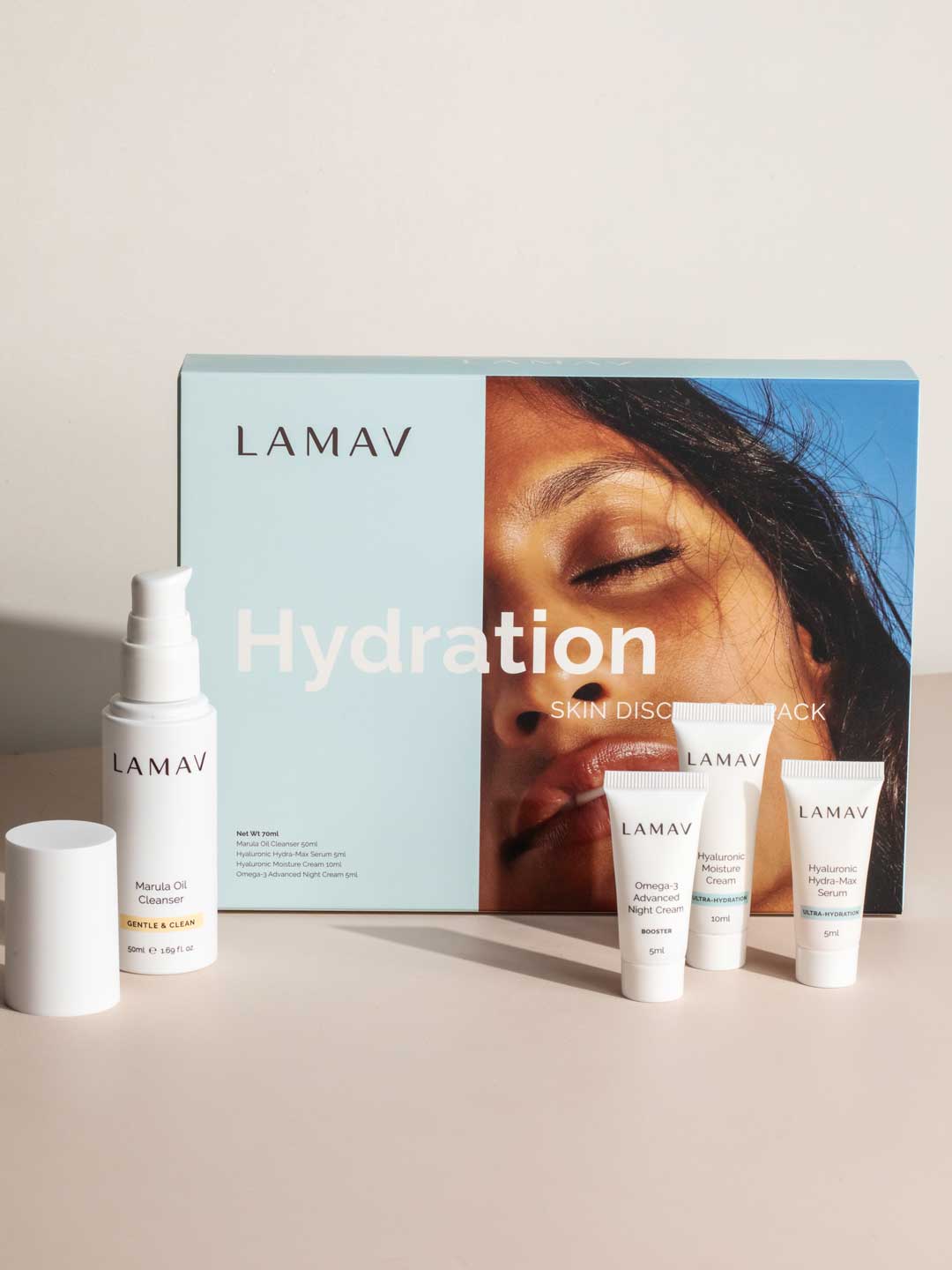 LAMAV Hydration Skin Discovery Pack (4 Pack) by LAMAV shown with a pump bottle, three small tubes, and a box featuring a sun-kissed face. This organic skincare set highlights hydrating care with hyaluronic acid on a neutral background.