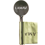 The LAMAV Tube Key—a shiny, round metal tool engraved with LAMAV—hangs from a pale green, folded fabric band featuring the logo, presented as a zero-waste beauty solution on a crisp white background.