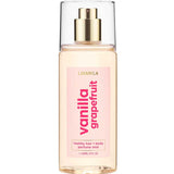 A clear spray bottle labeled Lavanila Healthy Hair and Body Mist Vanilla Grapefruit 150ml contains a pink vegan fragrance, features a gold spray nozzle with a transparent cap, and is marked “healthy hair + body perfume mist” at the bottom.