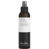 The Less is More Thyme Lacque 150ml is a certified organic hair spray in a minimalist black and white bottle, offering long-lasting hold.
