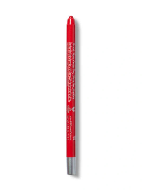 A bright red 100% Pure lip liner stands upright with its rounded red tip exposed. Small pale lettering runs down the back of the barrel, above a silver-coloured base.