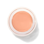 An open round pot of Golden Peach Long Last Concealer, viewed from above, showing smooth golden peach cream within a white rim.