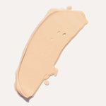 A swatch of Ere Perez Lychee Crème Corrector 10ml, a high-pigment light beige makeup, is spread on a white surface and labeled “Uno” below the swatch.