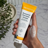 Hand holding an open white-and-yellow MooGoo Eczema and Psoriasis Cream tube marked 120g, with a thick white smear on the back of the hand.