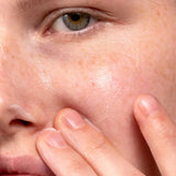 Close-up of a person with fair skin applying Madara Derma Collagen Peptide Serum 30ml by Madara to their cheek, showcasing smooth, hydrated skin and the anti-aging benefits of this serum in their skincare routine.