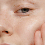 A close-up of a person’s radiant skin, highlighted by a gently touching hand, showcases the natural glow and clarity achieved with Madara Niacinamide Alternative 5-in-1 Serum 30ml by Madara—perfect for breakout-prone skin.