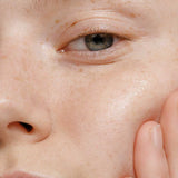 A close-up of a person’s radiant skin, highlighted by a gently touching hand, showcases the natural glow and clarity achieved with Madara Niacinamide Alternative 5-in-1 Serum 30ml by Madara—perfect for breakout-prone skin.