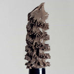 A close-up of the Madara Grow & Fix Tinted Brow Gel 4.25ml wand, coated with light brown product, showcases its textured bristles and detail against a plain light background.