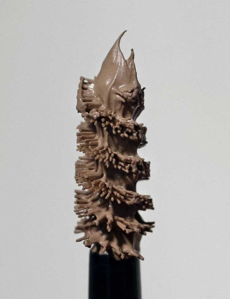 A close-up of the Madara Grow & Fix Tinted Brow Gel 4.25ml wand, its bristles coated with light brown vegan gel, set against a plain white background.