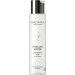 A 100ml white bottle of Madara Micellar Water with a silver cap and minimalist design. Suitable for all skin types, it removes makeup without rinsing. Contains hyaluronic acid and is vegan according to the label.
