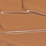 Madara Skin Equal Soft Glow Foundation SPF15 30ml in Caramel #70 swatched with glossy streaks and ripples, delivering a radiant, dewy finish. Colour: Caramel #70.
