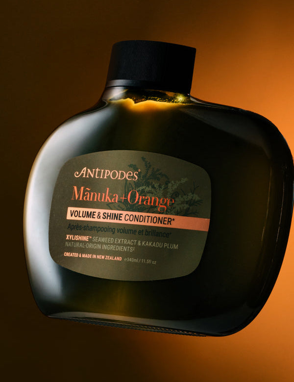 Antipodes Manuka and Orange Volume and Shine Conditioner bottle with product pour