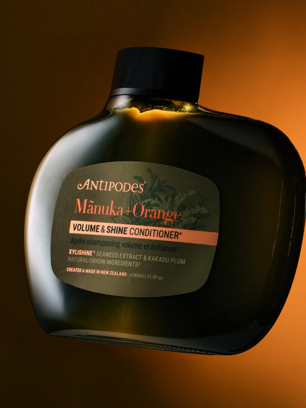 Antipodes Manuka and Orange Volume and Shine Conditioner bottle with product pour