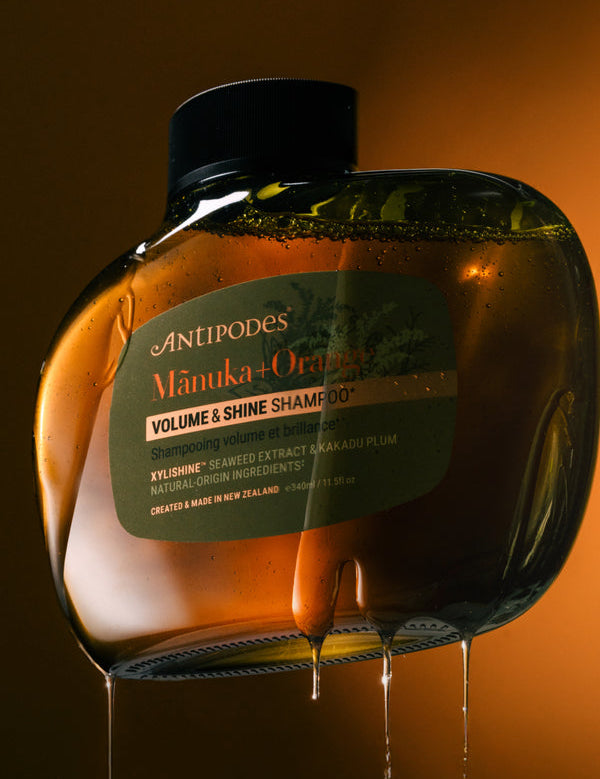 Antipodes Manuka and Orange Volume and Shine Shampoo bottle with product pour