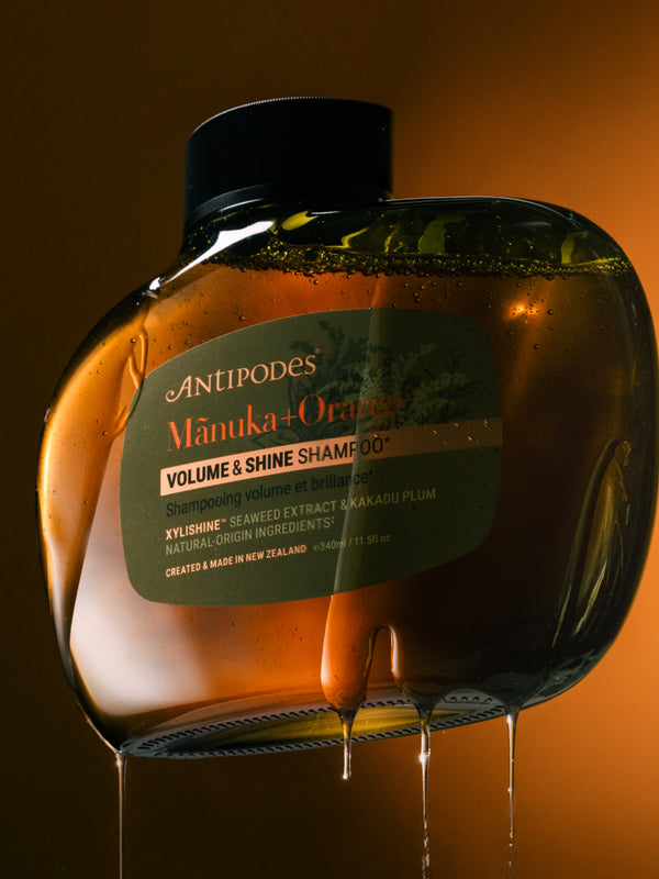 Antipodes Manuka and Orange Volume and Shine Shampoo bottle with product pour