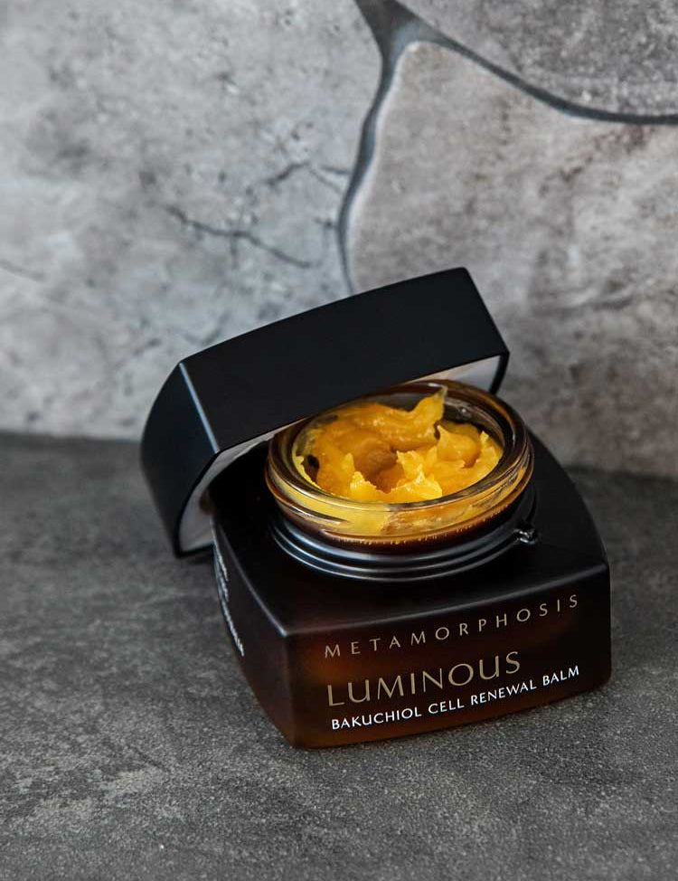 The Metamorphosis Luminous Bakuchiol Cell Renewal Balm 50ml, with its black jar and open lid revealing a rich yellow balm, is an ideal bakuchiol moisturiser and retinol alternative for menopausal skin.