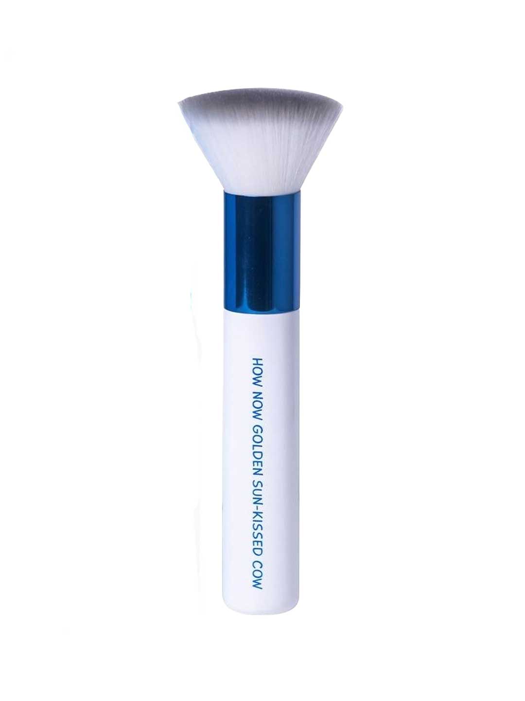 The MooGoo Tanning Blending Brush features a white handle with "HOLY MOLY GOLDEN SUN-KISSED GLOW" in blue, a blue metallic ferrule, and soft white bristles for streak-free self-tanner application.