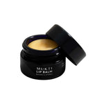 A black jar of Mukti Whipped Honey & Macadamia Lip Balm 9g with the lid resting beside it, showing the whipped golden balm made with certified organic ingredients.