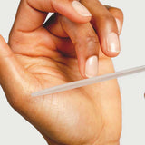 A close-up of a hand filing nails with the Sienna Byron Bay Glass Nail File, an eco-friendly and durable option, highlighting well-groomed fingers against a plain background.