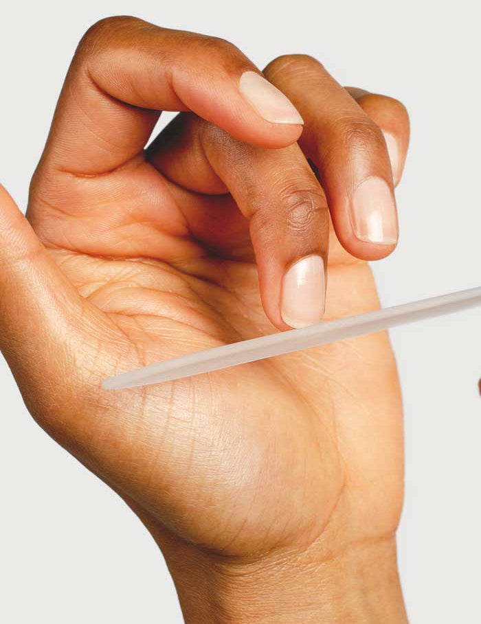 A close-up of a hand filing nails with the Sienna Byron Bay Glass Nail File, an eco-friendly and durable option, highlighting well-groomed fingers against a plain background.
