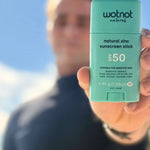 Man holding Wotnot Natural Zinc Sunscreen Stick SPF 50 at the beach