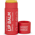 Noosa Basics Cherry lip balm in a red paper tube with a yellow balm stick visible at the top, shown with the cap removed on a white background.