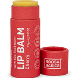 Noosa Basics Cherry lip balm in a red paper tube with a yellow balm stick visible at the top, shown with the cap removed on a white background.