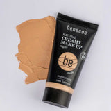 A 30ml tube of Benecos Natural Creamy Makeup sits on a white surface next to a smear of beige cream. The vegan, moisturising formula helps achieve a flawless finish.