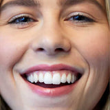 A close-up of a smiling woman with straight white teeth, wearing Luk Beautifood Lip Nourish Lipsticks 3g in nude pink. The text "Nude Pink" appears at the bottom of the image.