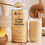 A 500g container of Nutra Naturals Clean Plant Protein Creamy Vanilla sits next to a glass of shake, a scoop of powder, bananas, and chickpeas on a wooden surface in warm, soft lighting.