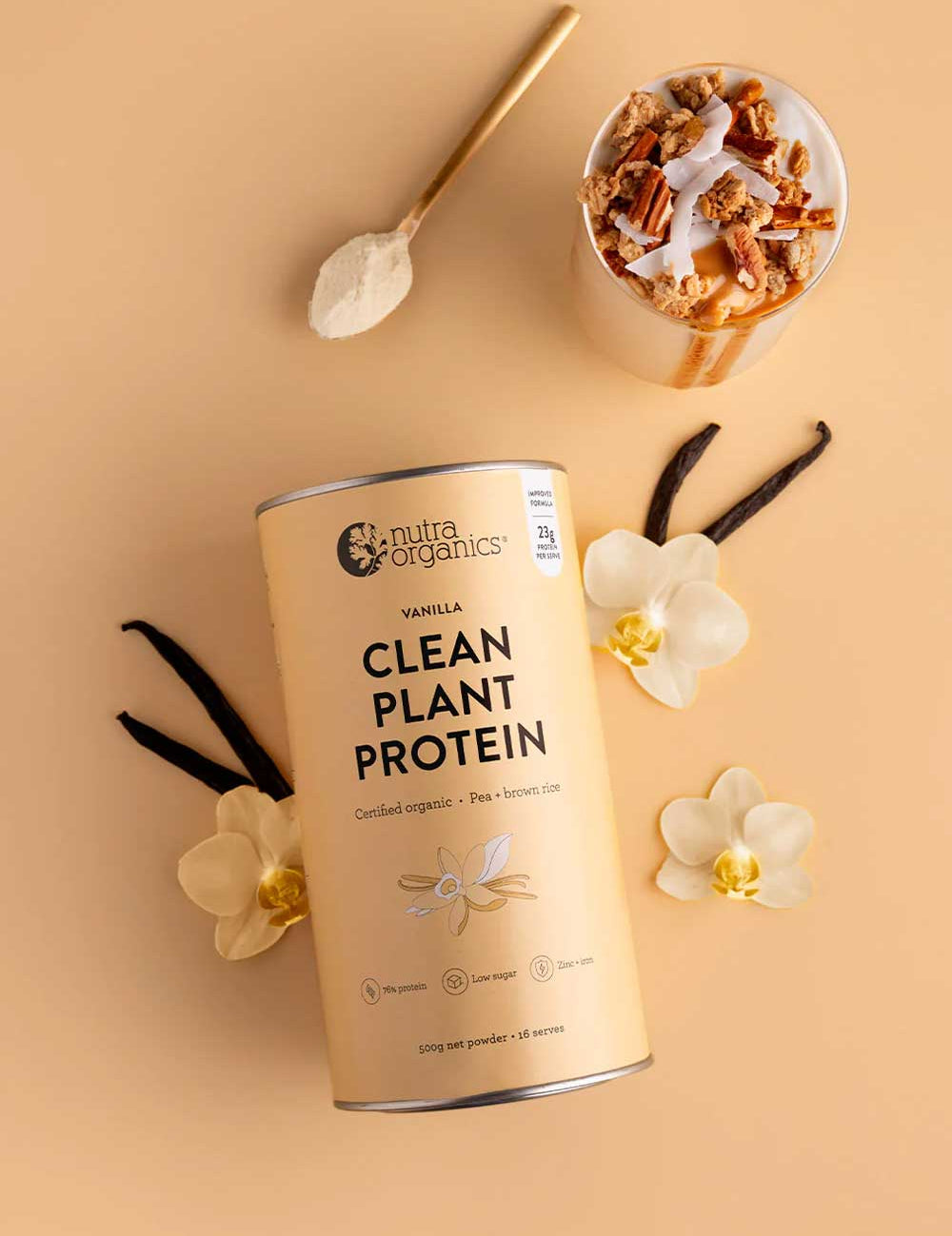 A canister of Nutra Naturals Clean Plant Protein Creamy Vanilla 500g sits on a beige surface alongside vanilla beans, white orchids, a gold spoon with powder, and a smoothie topped with granola and nuts.