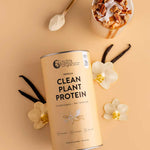 A canister of Nutra Naturals Clean Plant Protein Creamy Vanilla 500g sits on a beige surface alongside vanilla beans, white orchids, a gold spoon with powder, and a smoothie topped with granola and nuts.