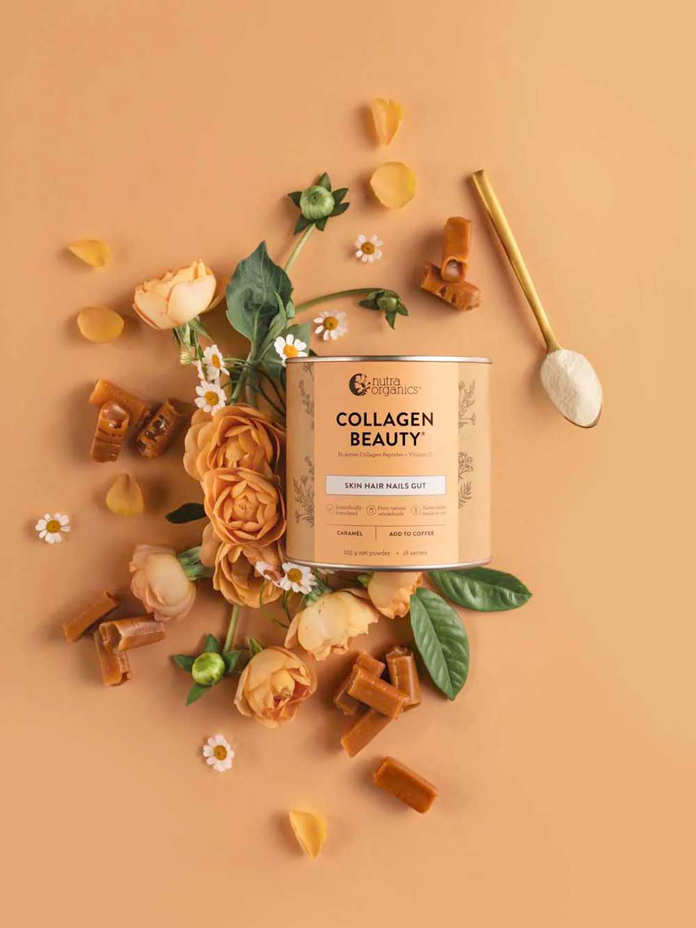 A container of Nutra Naturals Collagen Beauty Caramel 225g sits on a peach background, surrounded by orange roses, greenery, and caramel pieces. A gold spoon with white powder hints at enhanced skin hydration.