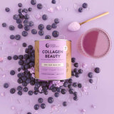 A canister of Nutra Naturals Collagen Beauty Blueberry Wildflower 225g is surrounded by blueberries, purple powder, and a glass of purple drink on a light purple background. A scoop of hydrolysed bovine collagen powder rests nearby.