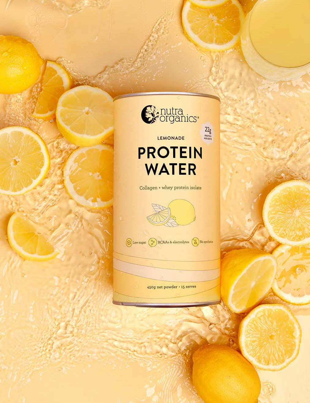 A canister of Nutra Naturals Protein Water Lemonade 450g, rich in electrolytes, is surrounded by sliced and whole lemons plus a glass of lemonade on a textured yellow surface with water splashes.