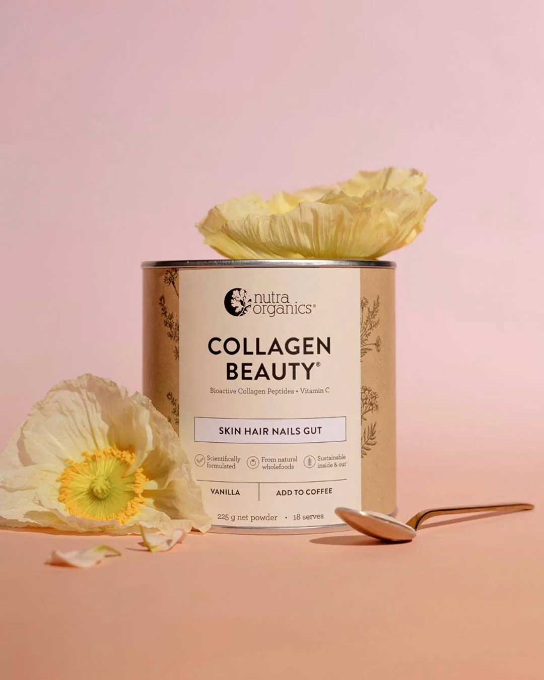 A container of Nutra Naturals Collagen Beauty Vanilla 225g is shown on a pink surface with pale yellow flowers and a gold spoon, featuring a label promoting benefits for skin, hair, and nails.