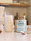 A creamy collagen powder drink with a straw sits next to a canister of Nutra Naturals Collagen Joints + Bones on a kitchen counter, emphasizing bone health support. A spoon lies nearby, with the softly blurred background adding warmth.