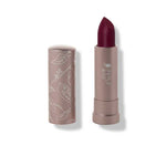 A 100% Pure Fruit Pigmented® Cocoa Butter Matte Lipstick (4.5g) in Oasis, a deep berry wine shade, is shown uncapped, revealing the rich lipstick and a taupe cap adorned with white botanical illustrations.