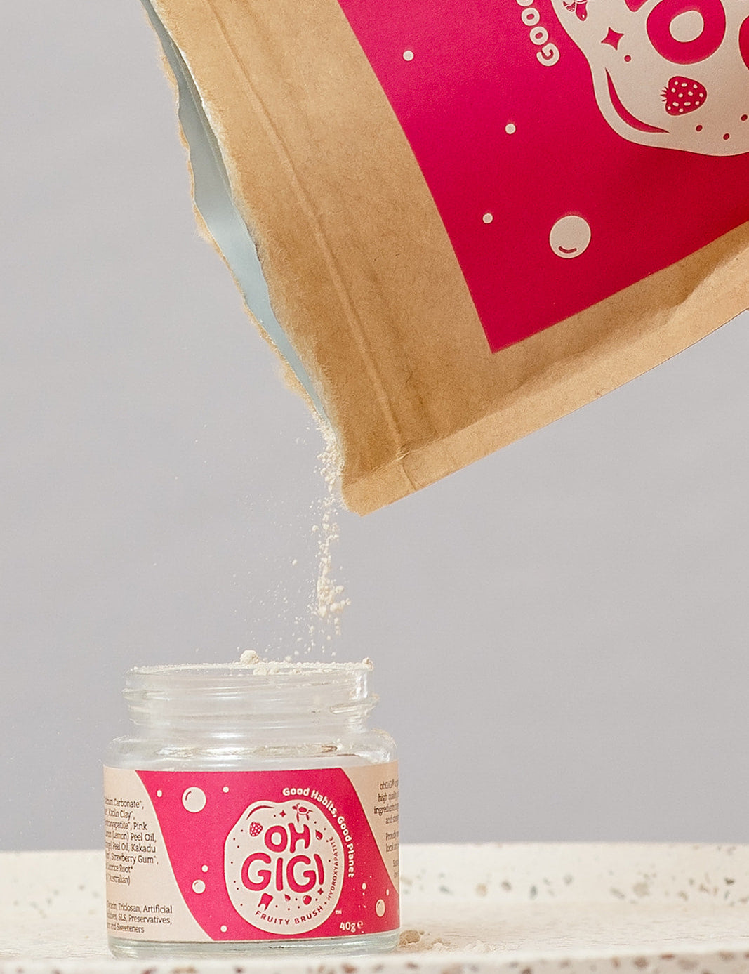 Oh Gigi Fruity Hydroxyapatite Tooth Powder refill being poured into its glass jar
