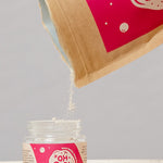Oh Gigi Fruity Hydroxyapatite Tooth Powder refill being poured into its glass jar