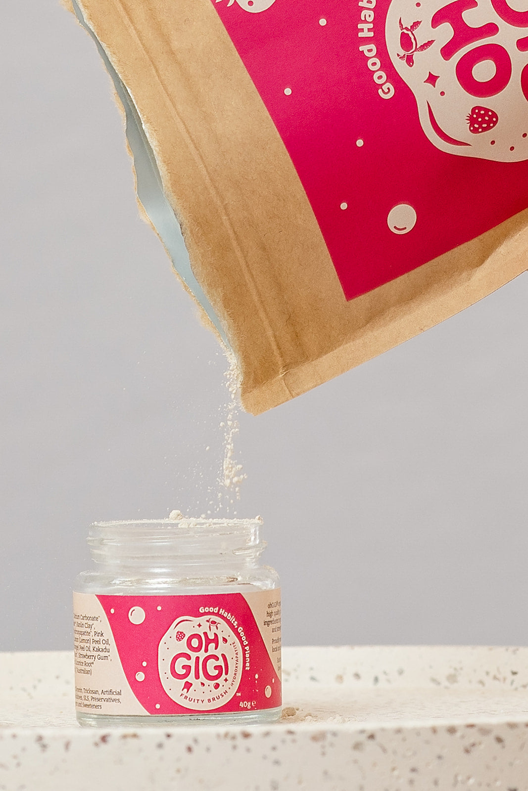 Oh Gigi Fruity Hydroxyapatite Tooth Powder refill being poured into its glass jar