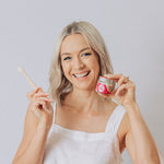 Woman smiling with a toothbrush and Oh Gigi Fruity Hydroxyapatite Tooth Powder