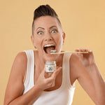 Woman holding Oh Gigi Flavour-Free Hydroxyapatite Tooth Powder and brushing her teeth